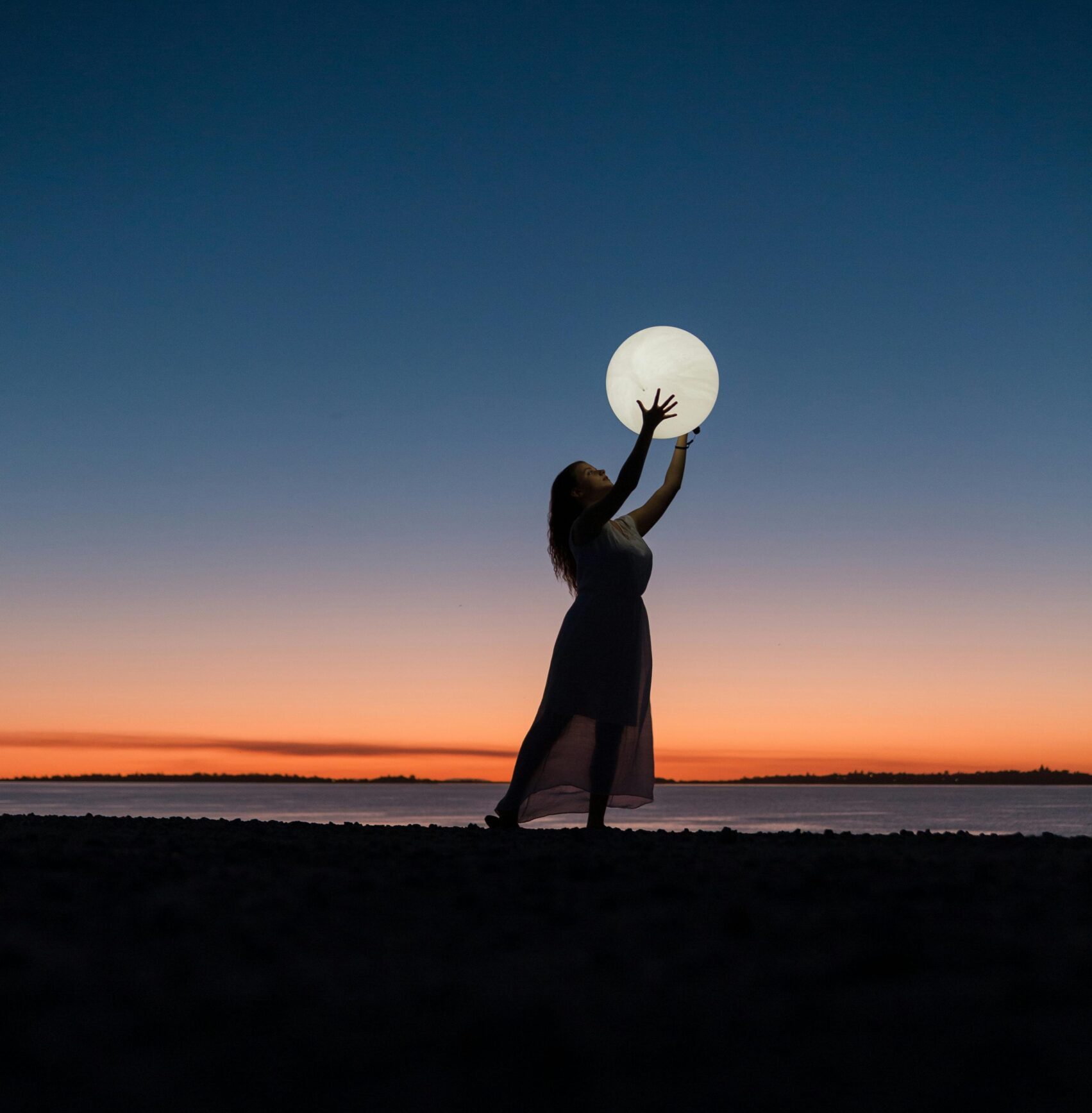 pexels-photo-3622517-3622517 A serene scene of a woman silhouetted against a sunset sky, reaching towards the full moon.